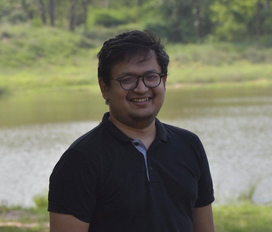 Utkarsh, smiling, beside a lake